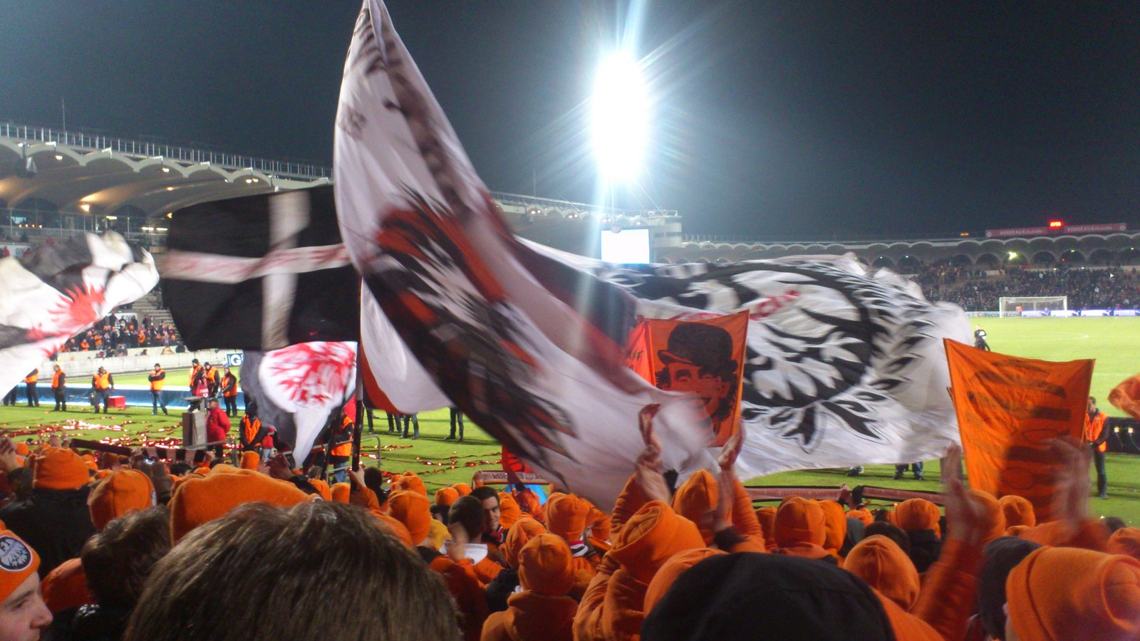 Eintracht fans in orange waving flags at the stadium in Bordeaux